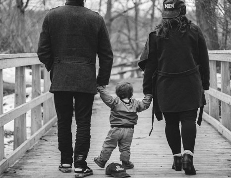 Mother and father walking with their baby outside.